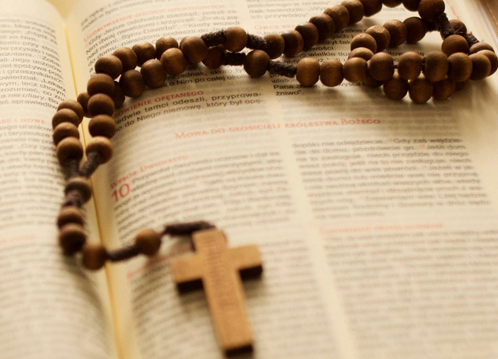 A wooden rosary is placed over an open Bible, symbolizing faith and devotion.